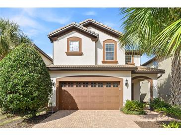 Two-story home featuring a brown tile roof, a brick driveway, and a two-car garage at 9026 Rhodes St, Kissimmee, FL 34747