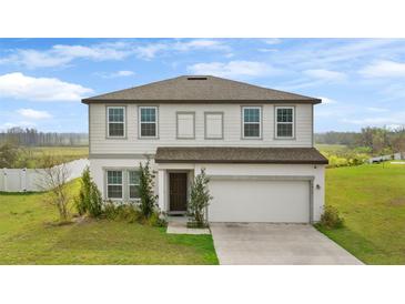 Charming two-story home featuring a well-maintained lawn, attached garage, and inviting front entrance at 16413 Bloom Ct, Groveland, FL 34736