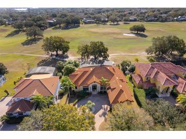 Expansive aerial view of a custom home with a tile roof overlooking a lush golf course and mature trees at 2313 Roat Dr, Orlando, FL 32835
