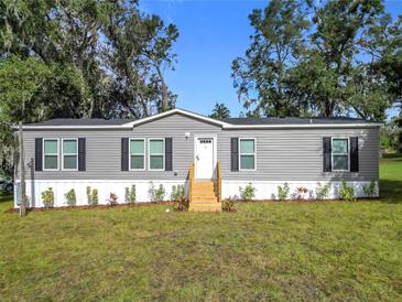 Charming gray home with black shutters and well-maintained landscaping at 5045 Se 148Th St, Summerfield, FL 34491