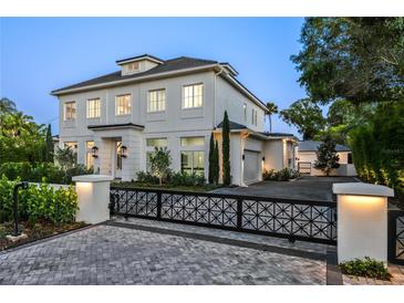 Stunning, light-colored, two-story home featuring manicured landscaping and a gated entrance at 1660 Palmer Ave, Winter Park, FL 32789