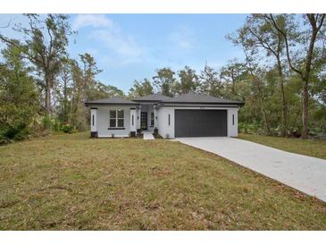 Inviting single-story home featuring a modern design, well-manicured lawn, and long driveway leading to a spacious garage at 2160 7Th Ave, Deland, FL 32724