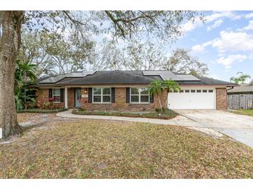 Charming brick home featuring a two-car garage, solar panels, and a well-maintained front yard at 432 Wilderness Dr, Longwood, FL 32779
