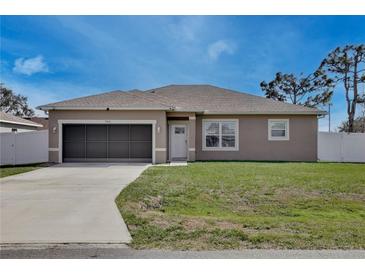 Charming single-story home featuring a well-manicured lawn and attached one-car garage at 702 Pelican Ct, Kissimmee, FL 34759