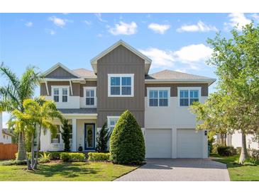 Beautiful two-story home featuring a manicured lawn, two-car garage, and charming front porch with a rocking chair at 9454 Becker Ct, Orlando, FL 32827