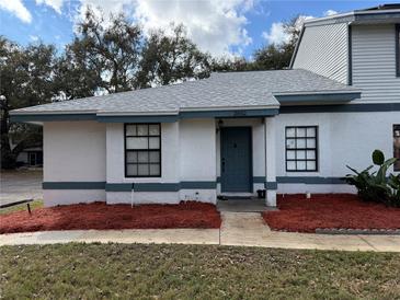 Charming one story home with a minimalist landscaped yard, front windows, and a blue entry door at 2652 Graduate Ct, Orlando, FL 32826