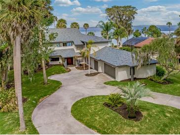 Stunning lakefront property with lush landscaping, a circular driveway, and an attached three-car garage at 303 Waterwood Dr, Yalaha, FL 34797