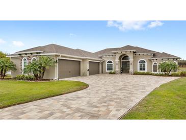 Stunning home featuring a three-car garage, paver driveway, lush landscaping, and elegant architectural details at 534 Two Lakes Ln, Eustis, FL 32726