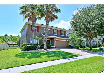 Two-story home featuring a well-manicured lawn, complemented by vibrant palm trees and red shutters, creating a welcoming curb appeal at 535 Belle Fern Ct, Ocoee, FL 34761