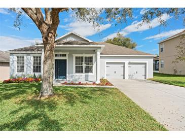 Charming single-story home with a manicured lawn, a tree, and a two-car garage at 581 Mary Paula Dr, Apopka, FL 32712