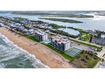 Beautiful aerial view of beachside condos with a pool and tennis court near the ocean at 6727 Turtlemound Rd # 417, New Smyrna Beach, FL 32169