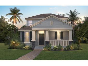 Charming two-story home featuring a welcoming front porch, well-manicured lawn, and tropical landscaping with palm trees at 18058 Cider Mill Ln, Winter Garden, FL 34787