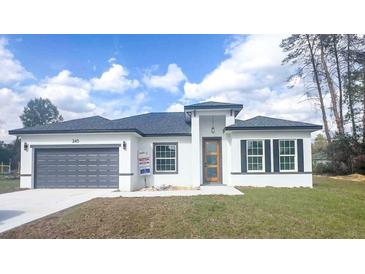 Charming single-story home showcasing a gray garage door, modern front door, and well-manicured lawn at 245 Marion Oaks Golf Rd, Ocala, FL 34473