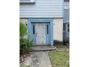 Charming townhome entrance with blue door frame and weathered white front door, palm on left at 3071 George Mason Ave # A, Winter Park, FL 32792