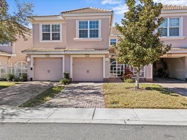 Charming townhome featuring a two-car garage, brick-paved driveway, and a well-maintained lawn at 1208 Bella Rose Ct, Davenport, FL 33896