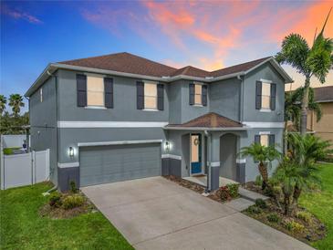 Charming two-story home featuring a well-manicured lawn and beautiful landscaping with palm trees under a vivid sky at 12627 Boggy Pointe Dr, Orlando, FL 32824