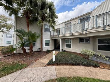 Condominium exterior featuring the building, sidewalk, manicured landscaping and healthy mature palm trees at 2564 Woodgate Blvd # 102, Orlando, FL 32822