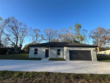 Charming single-story home with a well-maintained lawn, a gray exterior, and an attached garage at 6425 Curtis St, Orlando, FL 32807