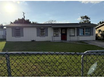 Charming single-story home with a red front door, tidy lawn, and a chain-linked fence at 7200 Ravenna Ave, Orlando, FL 32819