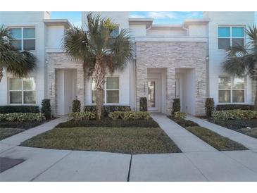 Contemporary townhome with stacked stone accents, manicured landscaping, and bright, modern facade at 17442 Hidden Forest Dr, Clermont, FL 34714