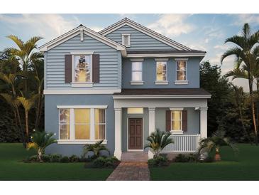 Charming two-story home with a covered porch, a well-manicured lawn and lush tropical landscaping at 18046 Cider Mill Ln, Winter Garden, FL 34787