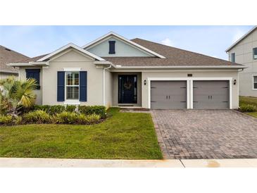Charming home with a well-manicured lawn and a two-car garage with a brick paved driveway at 18405 Mowry Ct, Orlando, FL 32827