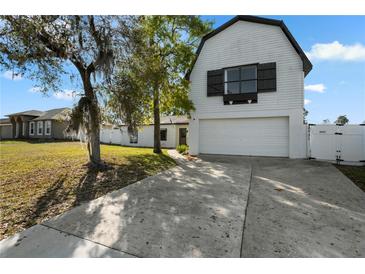Charming home featuring white siding, an attached two-car garage, and a well-maintained front yard with mature trees at 2531 Ludlow St, Deltona, FL 32738