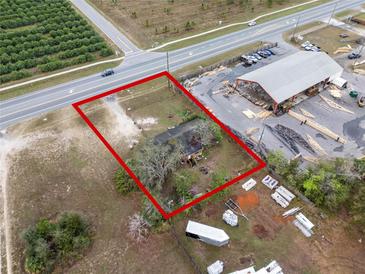 This aerial view showcases a property with a large lot and mature trees near a commercial area and roadways at 29650 State Road 19, Tavares, FL 32778