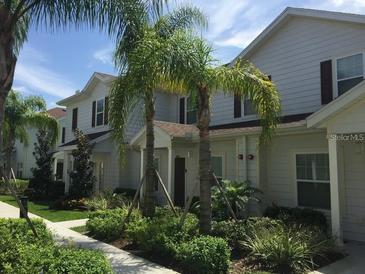 Townhome exterior with well-maintained landscaping, palm trees, and light-colored siding at 5352 Diplomat Ct # 107, Kissimmee, FL 34746