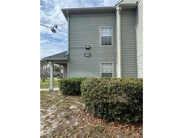 View of condo building 6100 with manicured bushes and neutral-colored siding at 6100 Westgate Dr # 203, Orlando, FL 32835