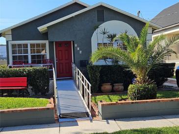 Charming single-story home with a well-manicured lawn, vibrant plants, and an accessibility ramp at 674 W Comstock Ave, Winter Park, FL 32789