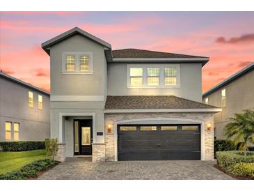 Two-story home showcases a gray facade, stone accents, and a paved driveway leading to a two-car garage at 7419 Marker Ave, Kissimmee, FL 34747