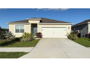 Charming single-story home features a well-manicured lawn, two-car garage, and a blue front door at 1003 Cascade Dr, Davenport, FL 33837