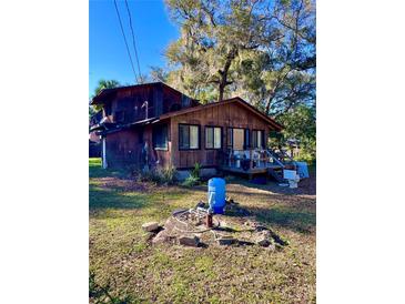 Rustic two-story home featuring a wood exterior, a small porch, and mature trees in a partially sunny yard at 11290 Se 189Th Ct, Ocklawaha, FL 32179