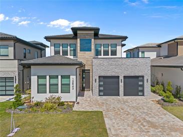 Contemporary two-story home boasts a paver driveway, two-car garage and manicured landscaping at 15843 Vetta Dr, Bella Collina, FL 34756