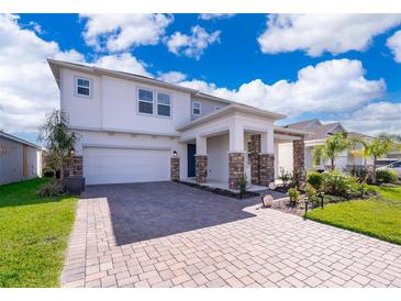 Charming two-story home with a brick driveway, landscaped yard, and a covered entryway at 187 Aces High Ln, Davenport, FL 33896