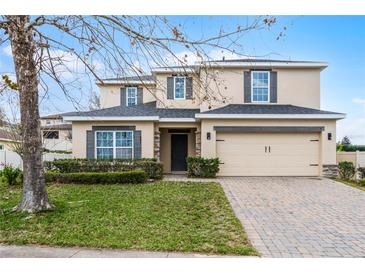 Charming two-story home with neutral stucco, manicured lawn, paver driveway, and attached two-car garage at 9518 Lynwood St, Clermont, FL 34711