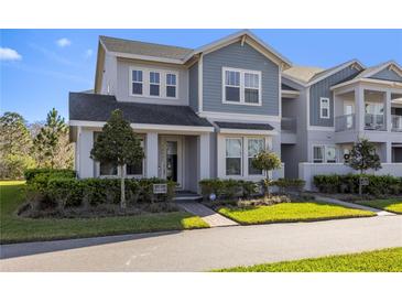 Charming two-story townhome with a blend of gray and blue siding and landscaped front yard at 14031 Centerline Dr, Orlando, FL 32827