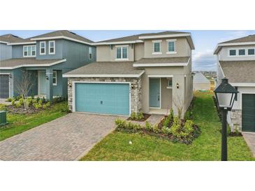 Charming two-story home featuring a blue garage door, stone accents, and a well-manicured lawn at 1988 Sunshine Peak Dr, Minneola, FL 34715