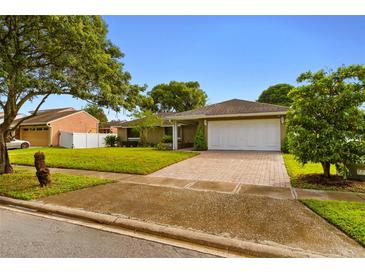 Charming single-story home with a well-manicured lawn and a brick-paved driveway at 211 S Deerwood Ave, Orlando, FL 32825