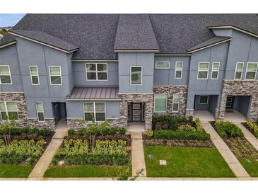 Modern townhome exterior with stone accents, lush landscaping, and a stylish front door at 2182 Cooper Bell Pl, Kissimmee, FL 34747