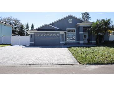 Charming single-story home showcasing a gray exterior, two-car garage and meticulously landscaped yard at 2324 Merrimack Dr, Kissimmee, FL 34743