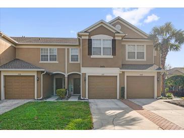 Inviting townhome showcasing a neatly manicured lawn, with a private garage and walkway leading to the front door at 2851 Polvadero Ln # 107, Orlando, FL 32835