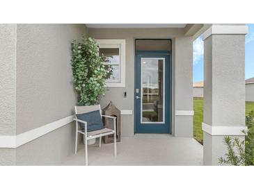 Inviting front porch featuring a chair, accent table, and a stylish blue front door at 3603 Salvia Ct, Tavares, FL 32778