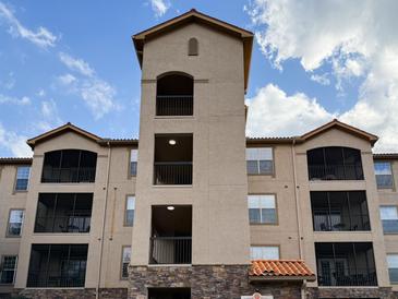 Stunning exterior view of a multi-story building with balconies, under a beautiful blue sky with scattered clouds at 8010 Tuscany Way # 5206, Davenport, FL 33896