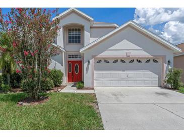 Charming two-story home featuring a red front door, manicured lawn, and an attached two-car garage at 963 Cherry Valley Way, Orlando, FL 32828