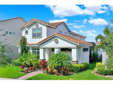 Inviting two-story home featuring a red tile roof, manicured lawn, and lush, colorful landscaping at 10249 Beechwood Ln, Orlando, FL 32832