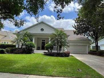 Charming single-story home features lush landscaping, a well-manicured lawn and a welcoming front porch at 11474 Claymont Cir, Windermere, FL 34786