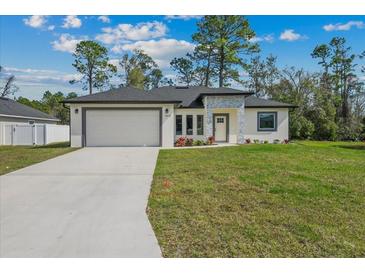 Charming single-story home boasts a lush lawn, a two-car garage, and tasteful stone accents around the front door at 2875 E Slater Dr, Deltona, FL 32738