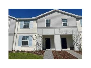 Charming two-story townhouse with neutral siding, light blue shutters and well-maintained landscaping at 4058 Lana Avenue, Davenport, FL 33897